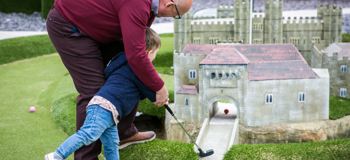 Grandpa playing adventure golf with grand daughter